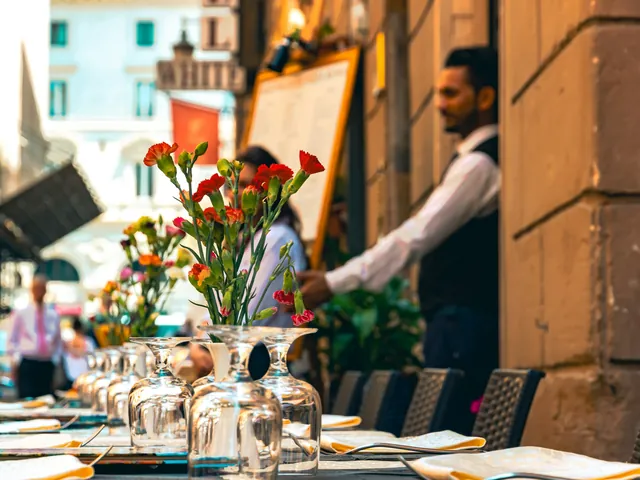 A server laying a table on a sunlit terrace